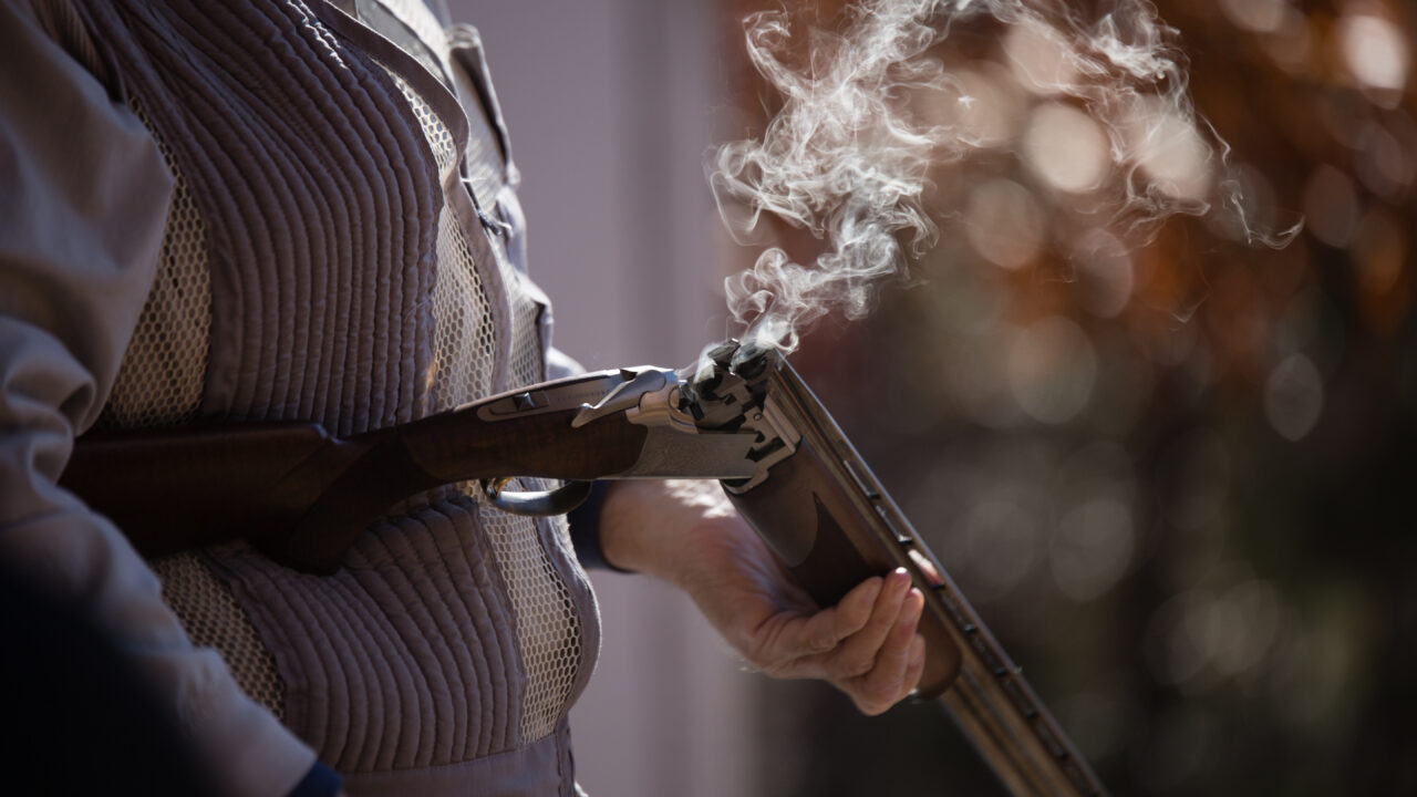 Shooter with an open breach shotgun with smoke coming out