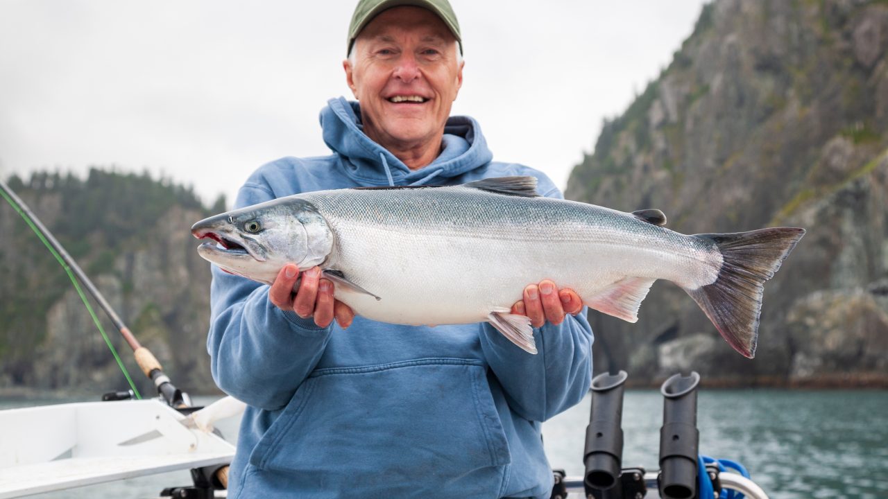 Fisherman holds up a salmon caught in Alaska.